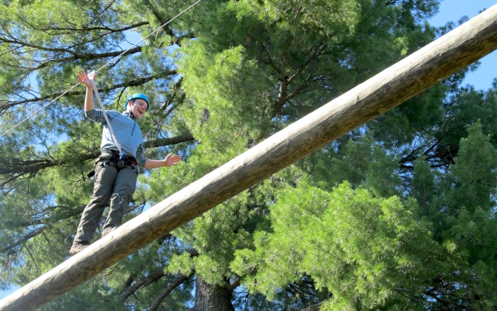 a person balances on a beam during a ropes course challenge